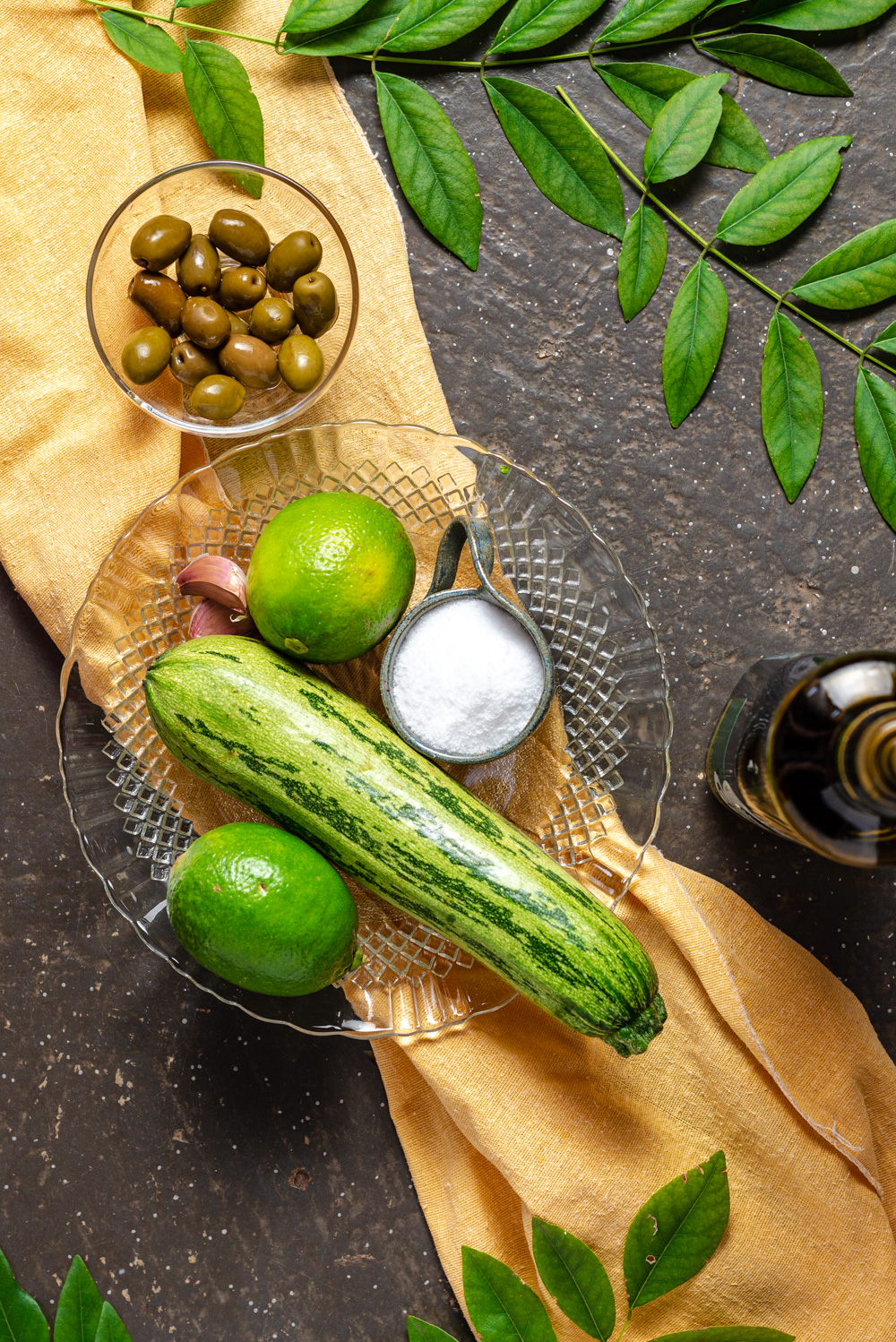 zucchini, salt, limes, olives and olive oil on a table