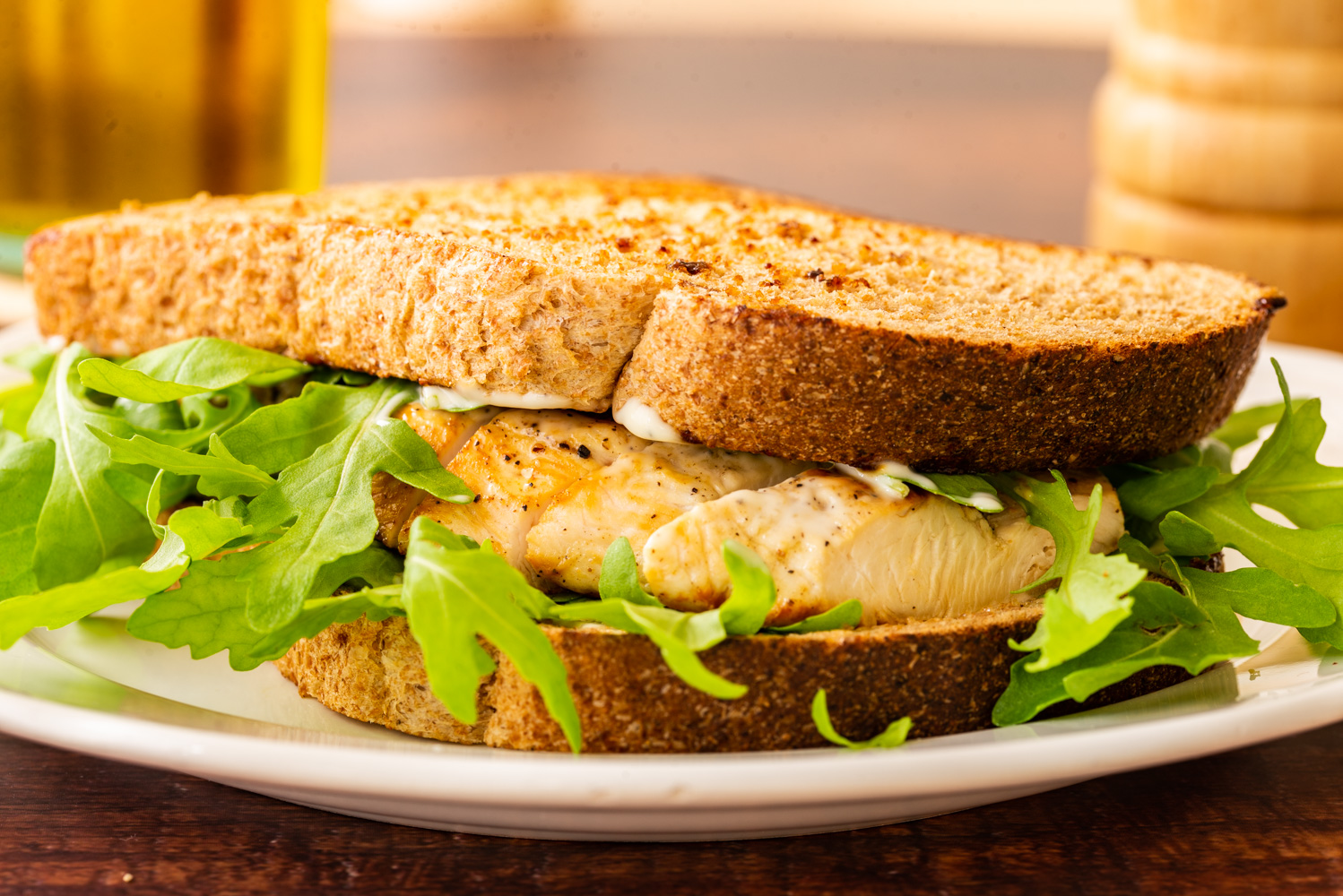 grilled chicken breast sandwich with watercress on a white plate