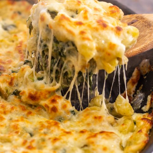 spoonful of macaroni cheese with spinach and artichoke