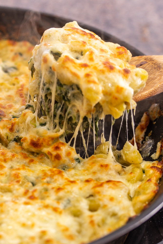 spoonful of macaroni cheese with spinach and artichoke
