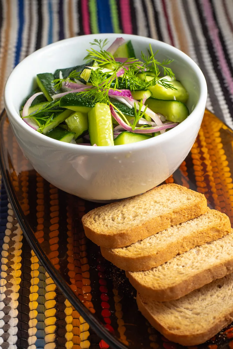 cucumber and dill salad in a bowl with bread toasts