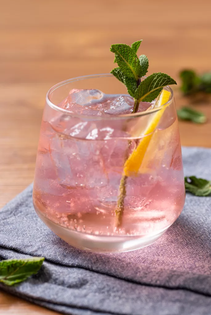 close up shot of a pink whitney drink with mint and lemon round