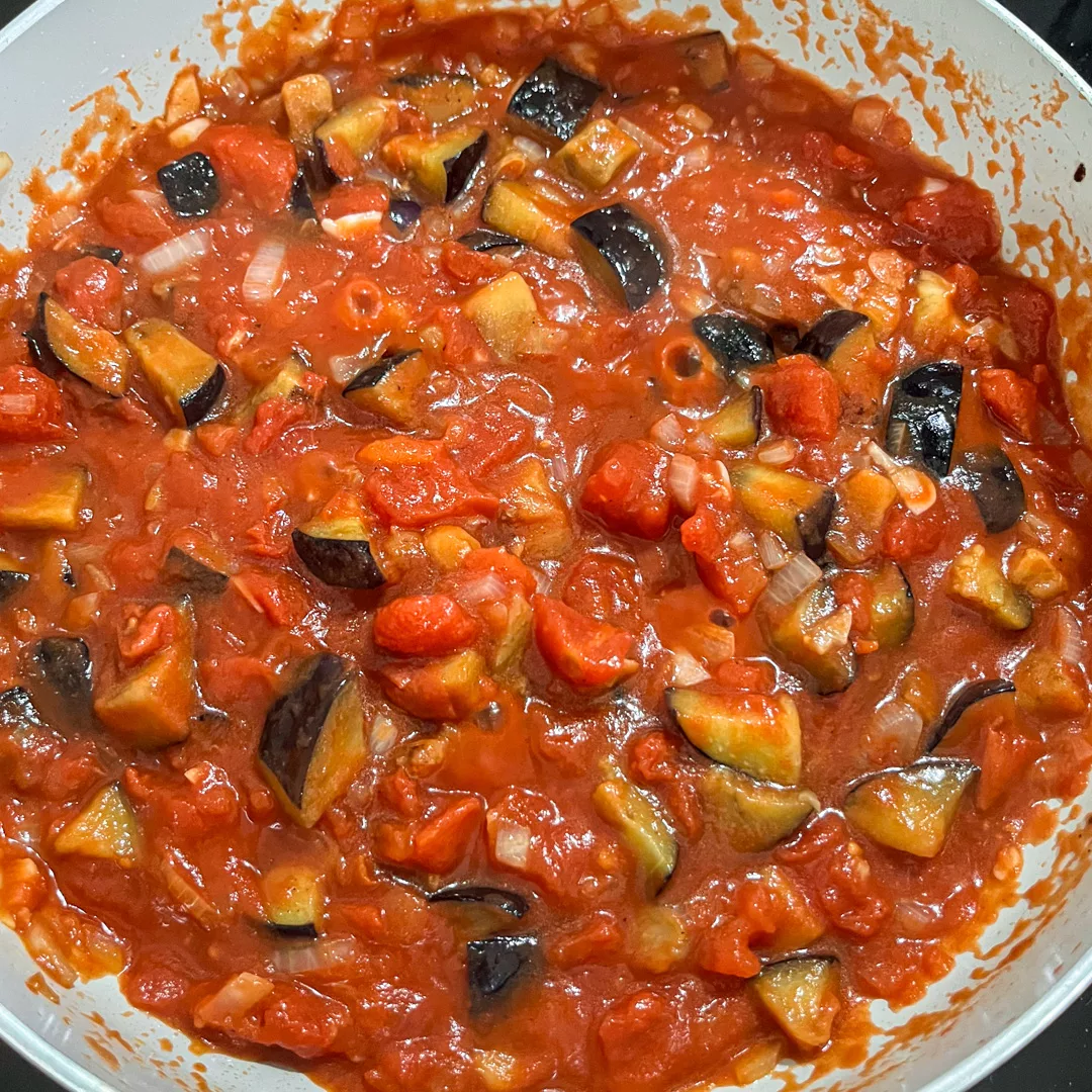 top view of skillet with tomato sauce cooking with eggplant