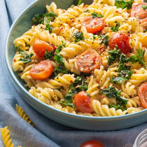 top view of a bowl with cherry tomatoes and kale fusilli pasta