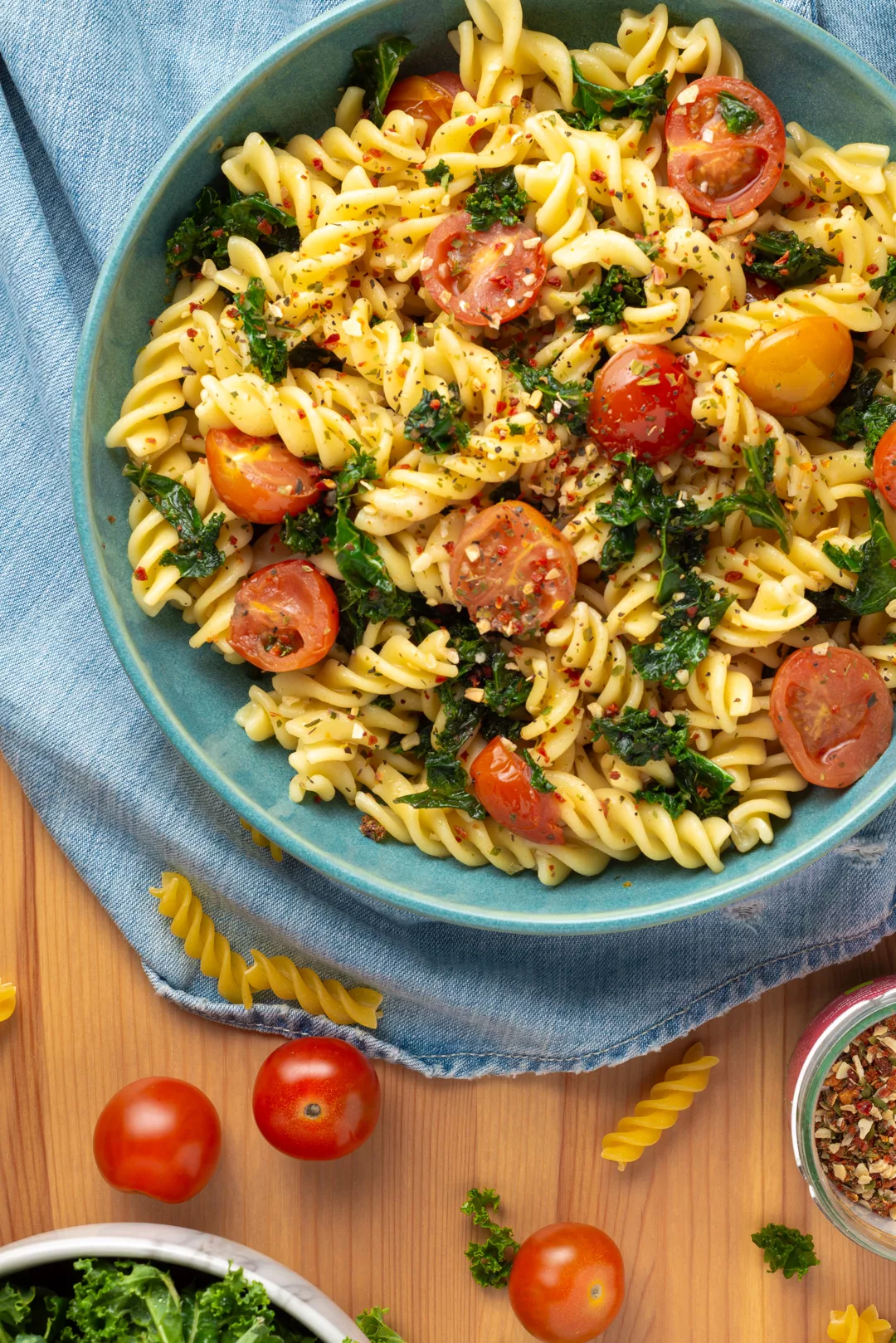top view of a bowl of tomatoes and kale pasta on a table