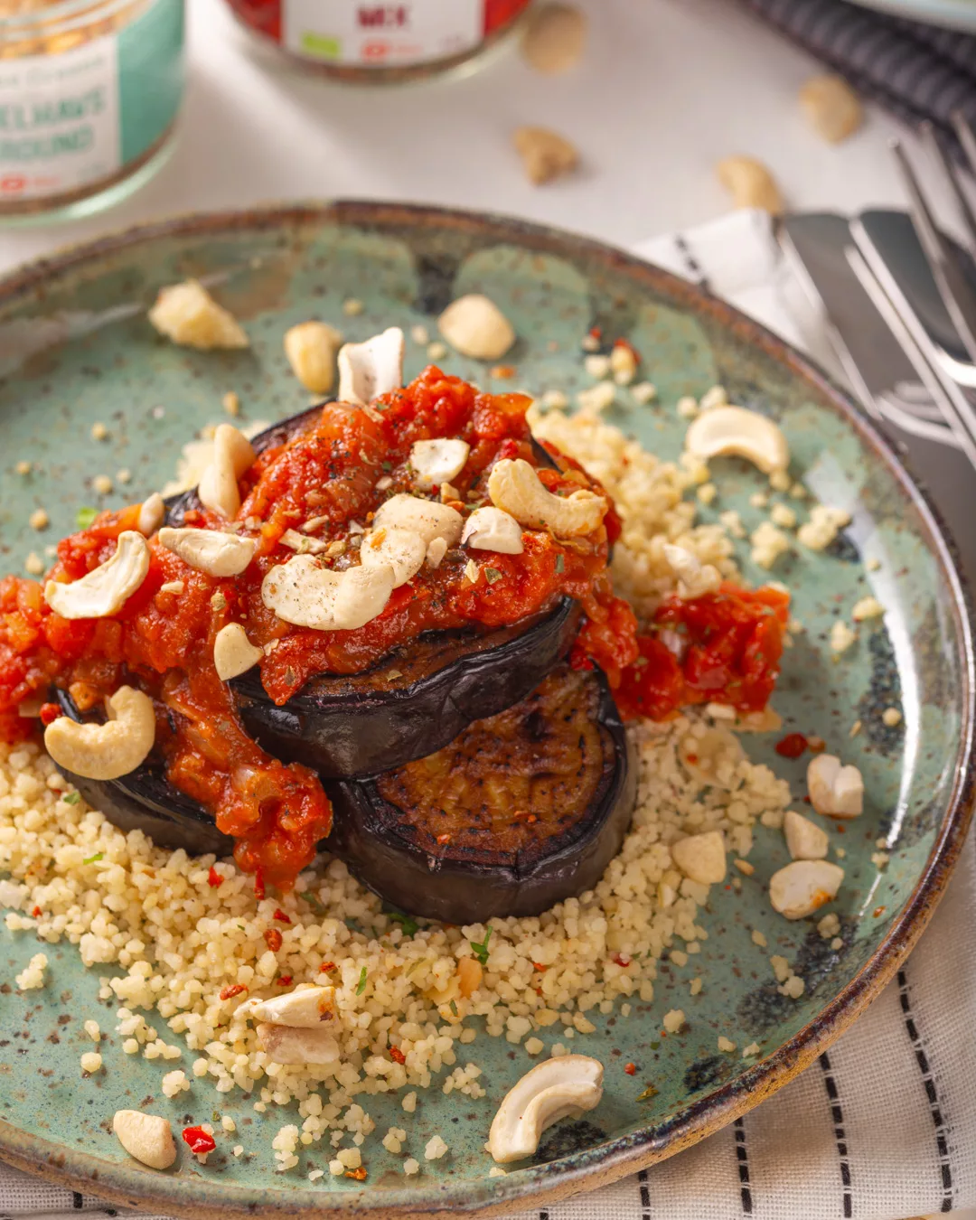 front image of a plate with eggplant topped with tomato juice on a bed of couscous