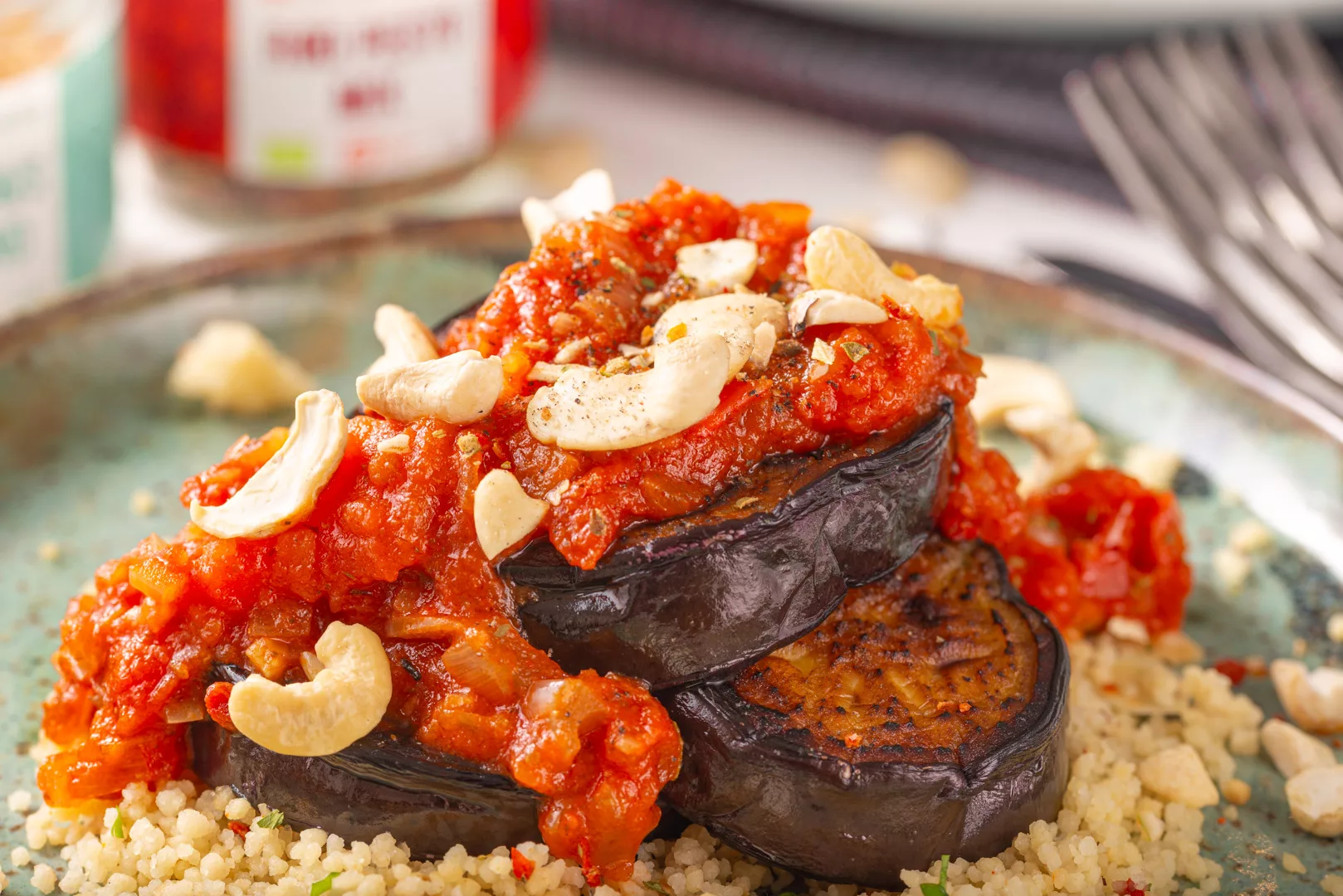 front image close up of a plate with eggplant topped with tomato juice on a bed of couscous