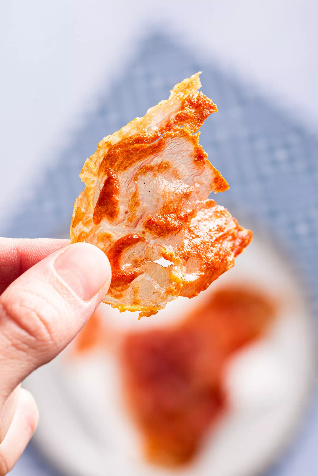 a piece of crisp prosciutto being held with fingers